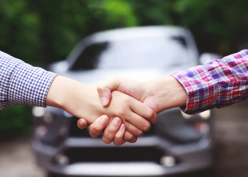 two people shaking hands on a deal to purchase a car with cash
