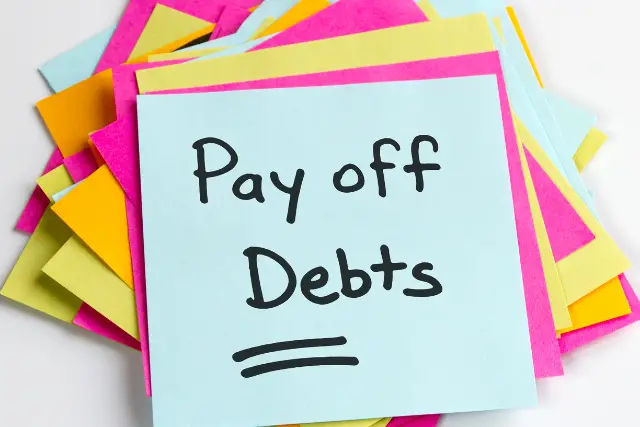 Sticky note with the words "pay off debts"