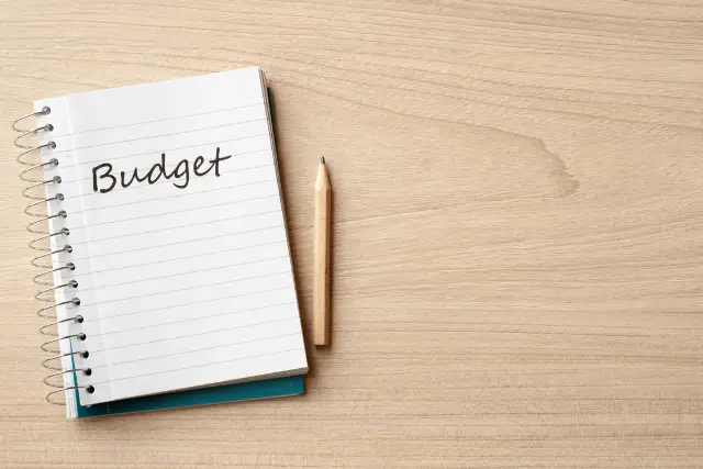 Notepad that has the word "Budget" written on it wiht a pencil 