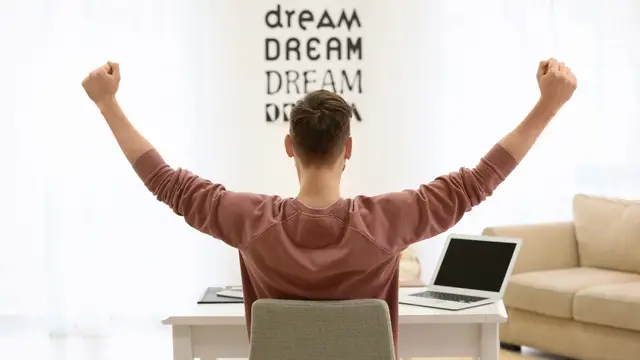 Person with both arms in the air at their computer desk