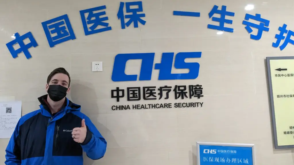 Me in the Health Insurance building with the writing on the wall that says "China Healthcare Security"